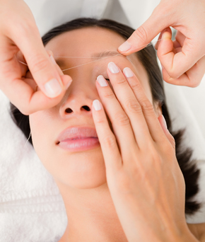 Close up view of hands threading beautiful womans eyebrow